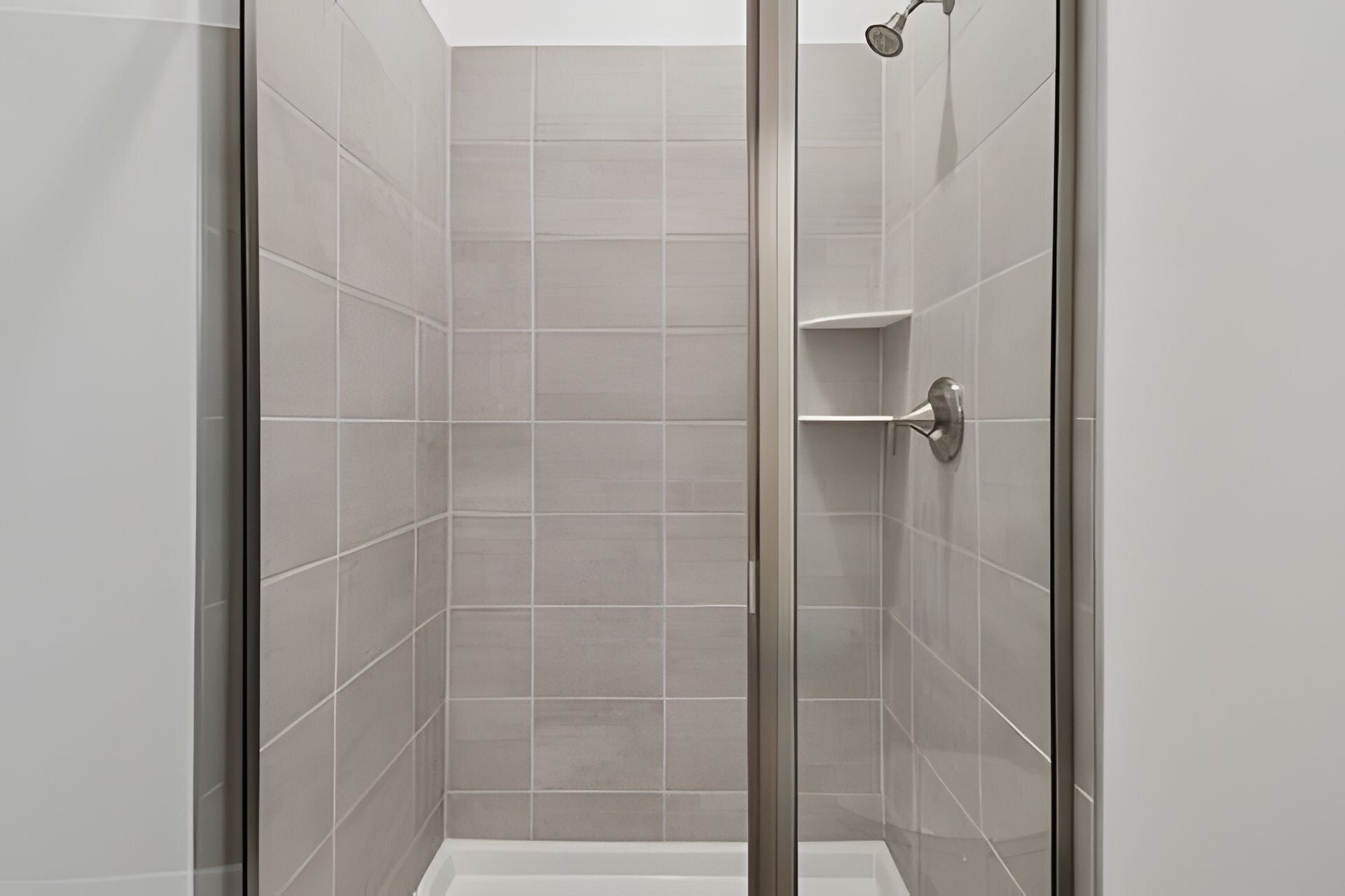 A modern shower enclosure with a glass door and a showerhead.