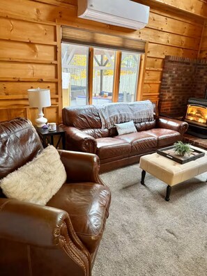 A cozy log cabin interior with a leather sofa, a coffee table, and a fireplace.