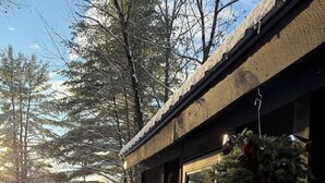 Een houten gebouw met een met sneeuw bedekte grond, een kerstkrans en een gedeeltelijk zichtbare deur.