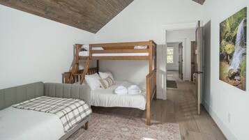 Un dormitorio con una cama nido, un sofá cama, un tapete estampado y un cuadro de una cascada.