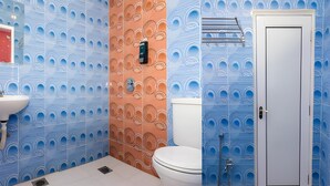 Un baño con baldosas azules y anaranjadas con diseño, un lavamanos blanco, un inodoro y una zona de ducha.