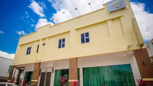 Un hotel con fachada amarilla, múltiples ventanas y un letrero que dice 'Gold City Hotel'.