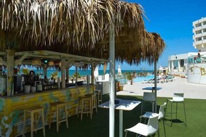 A beachside bar with a thatched roof, outdoor seating, and a view of the ocean. - On Hotels Oceanfront Adults Designed (Almonte)