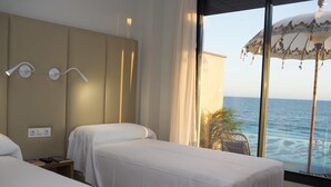 A hotel room with two beds, a large window with a view of the sea, and a ceiling fan. - On Hotels Oceanfront Adults Designed (Almonte)