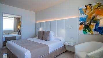 Una habitación de hotel moderna con una cama grande, una mesita de noche, una silla y un cuadro en la pared.
