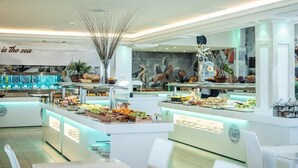 A modern buffet setup with various food items and a decorative centerpiece. - On Hotels Oceanfront Adults Designed (Almonte)