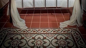 A bed with a canopy, a nightstand, and a patterned floor. - Villa Amalia (Rhodes)