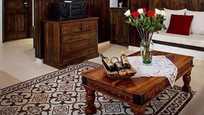 A spacious living room with a wooden staircase, a television, a wooden coffee table, and a patterned rug. - Villa Amalia (Rhodes)