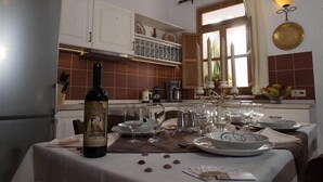 A dining area with a table set for a meal, a bottle of wine, and various dishes. - Villa Amalia (Rhodes)