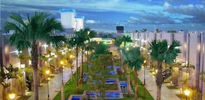 Un patio de hotel con palmeras, una fuente de agua y un edificio moderno al fondo.