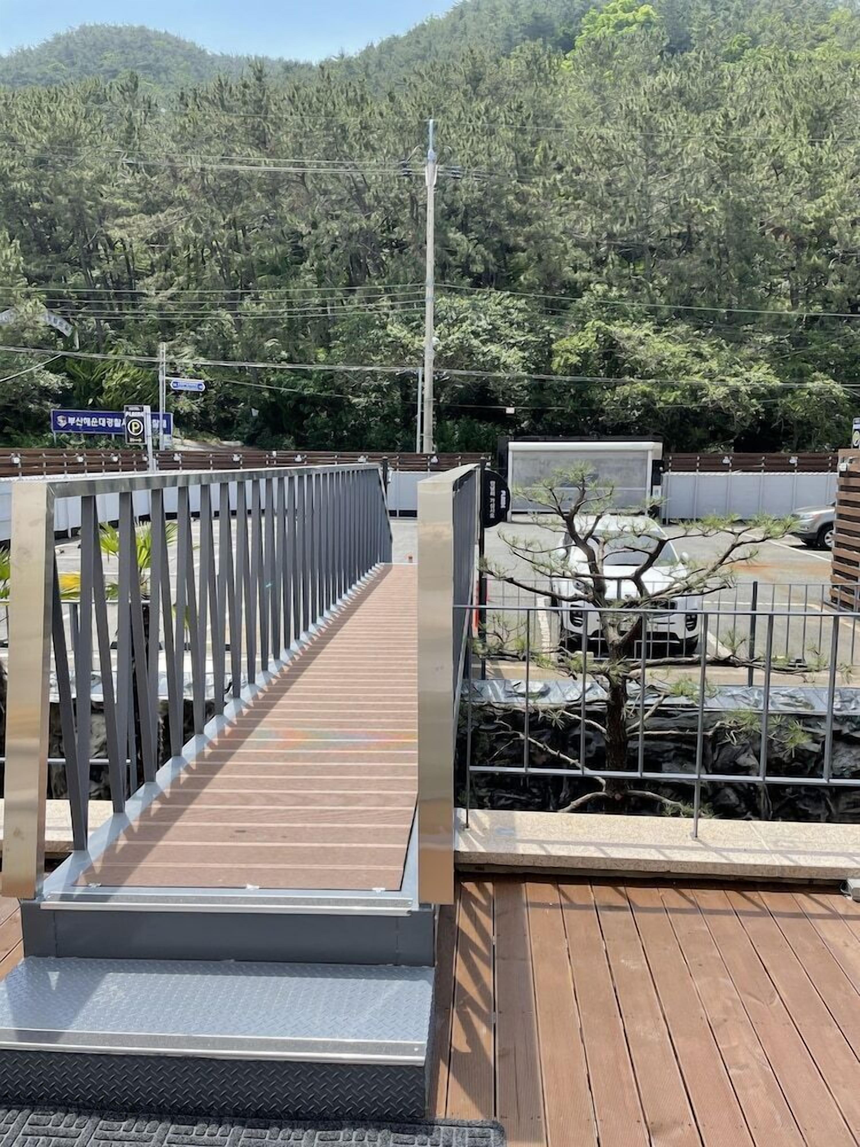 A wooden deck with a metal railing, a metal staircase, and a view of a forested hillside.