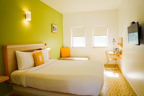 A hotel room with a bed, a desk, a chair, a TV, and two windows. - Bloomrooms @ Calangute (Candolim)