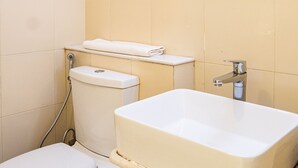 A bathroom with a toilet, sink, and a hand wash dispenser. - Bloomrooms @ Calangute (Candolim)