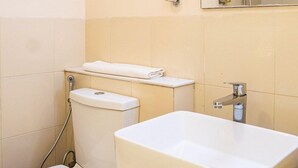 A bathroom with a toilet, a sink, and a mirror. - Bloomrooms @ Calangute (Candolim)