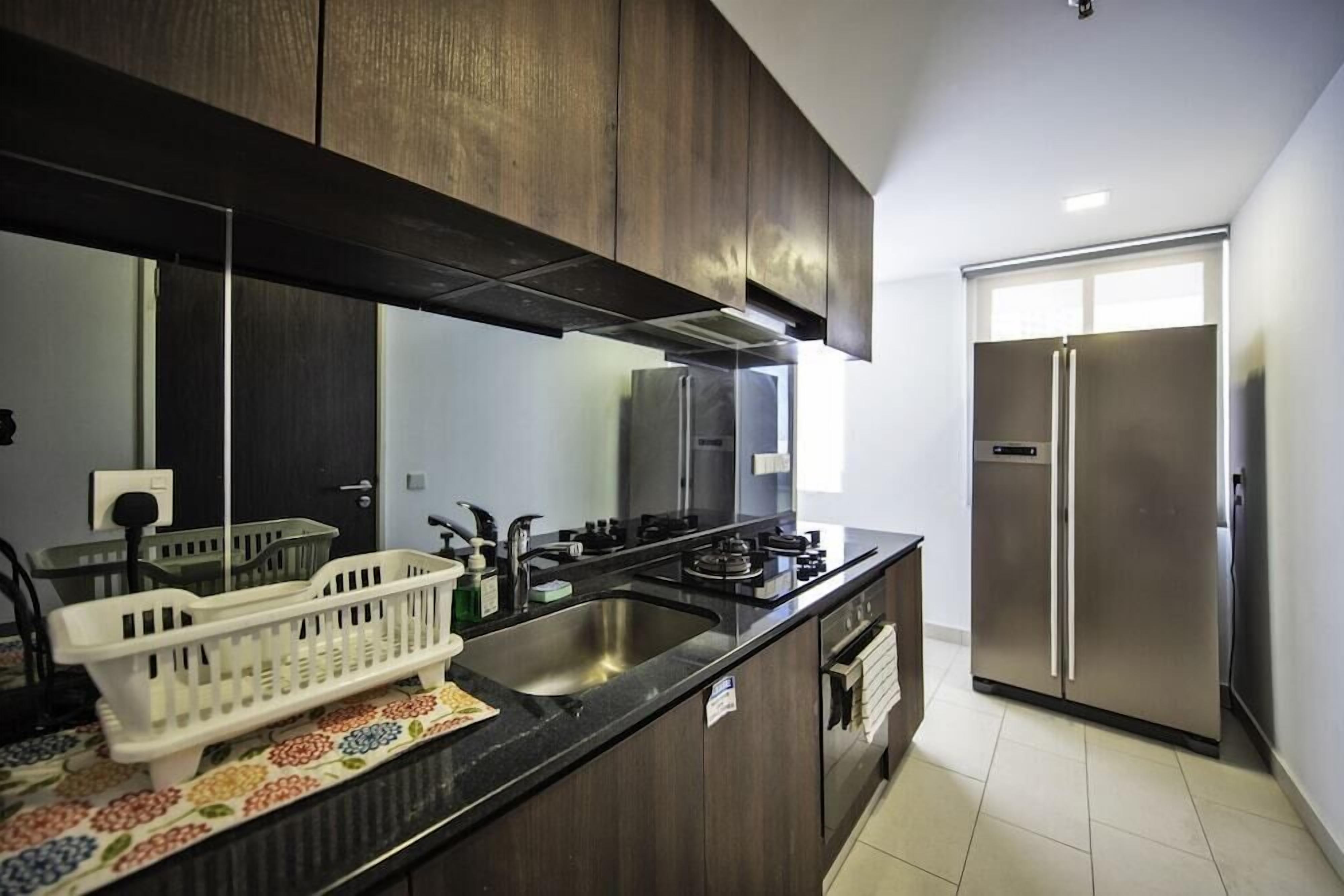 A modern kitchen with dark wooden cabinets, stainless steel appliances, and a black countertop.