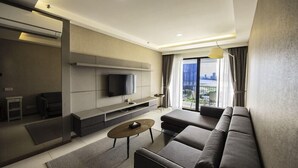 A modern living room with a sofa, a coffee table, and a flat-screen TV mounted on the wall. - The Landmark Studio Suite (George Town)