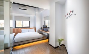 Ein modernes Hotelzimmer mit Bett, Schreibtisch und Blick auf die Stadt.