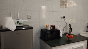 A kitchen with a microwave, a small refrigerator, and a countertop with a bowl of fruit.