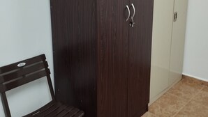 A dark wooden wardrobe with two doors, a bench, and a tiled floor.