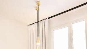 A modern bedroom with a wooden bed, a desk with a yellow chair, a black chair, and a large window with curtains. - Smartment Business Berlin Karlshorst (Berlin)
