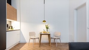 A modern kitchen with wooden cabinets, a dining table with two chairs, and a pendant light. - Smartment Business Berlin Karlshorst (Berlin)
