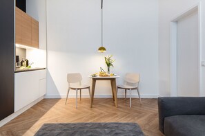 Een moderne keuken met houten kastjes, een eettafel met twee stoelen en een hanglamp.