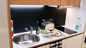 A modern kitchen with a stainless steel sink, a toaster, a bottle of water, and a bowl of salad. - Smartment Business Berlin Karlshorst (Berlin)