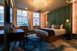 A hotel room with a bed, a desk, a chair, a large window with curtains, and a brick wall. - Velvet Hotel Manchester, Worldhotels Crafted (Manchester)