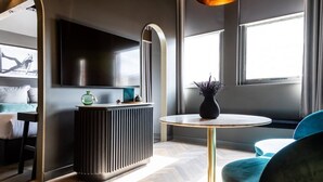 A modern living room with a round table, a sofa, a radiator, and a TV mounted on the wall. - Velvet Hotel Manchester, Worldhotels Crafted (Manchester)