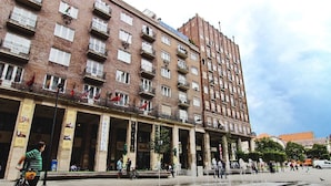 A multi-story building with balconies, a fountain, and people around. - Absolut City Hostel Budapest (Budapest)