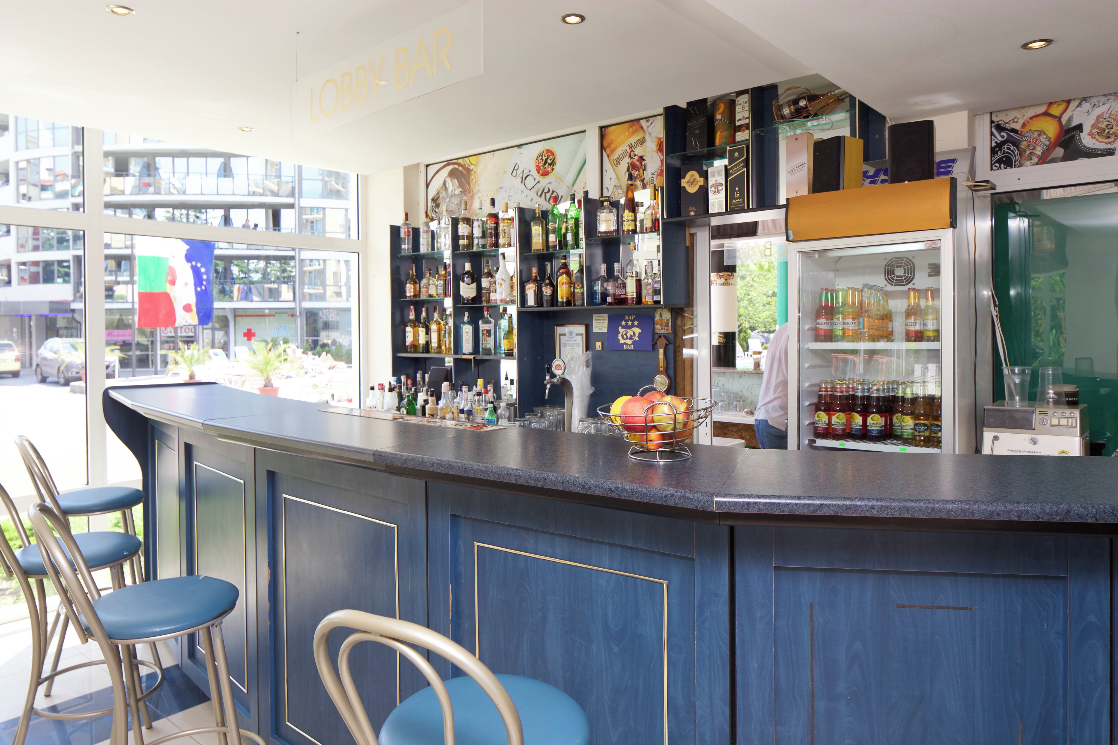 A bar area with a counter, stools, and shelves of bottles.