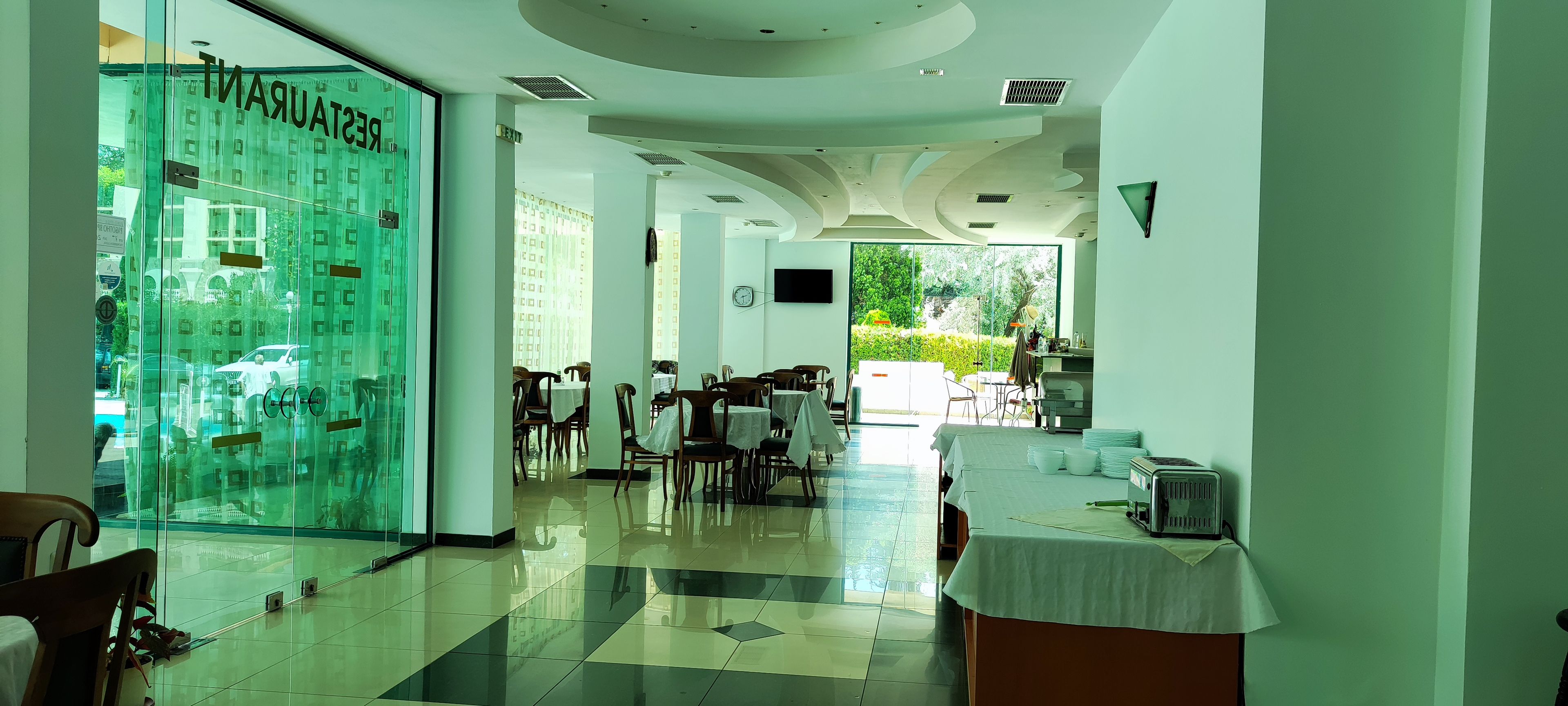 Un restaurante con pared de vidrio, mesas, sillas y vistas al exterior.