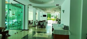 Un restaurante con pared de vidrio, mesas, sillas y vistas al exterior.