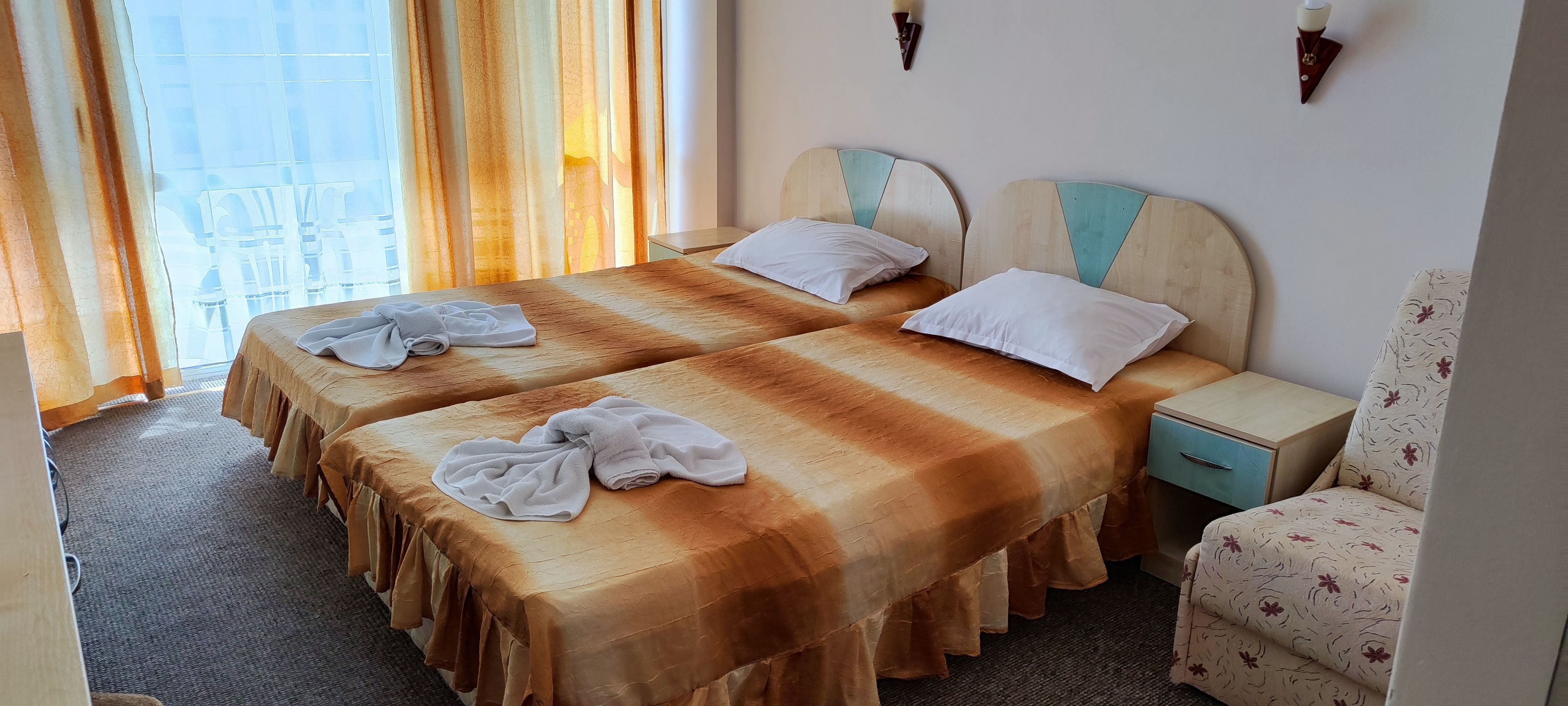 A hotel room with two beds, a chair, and a nightstand.