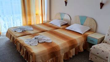 A hotel room with two beds, a chair, and a nightstand.