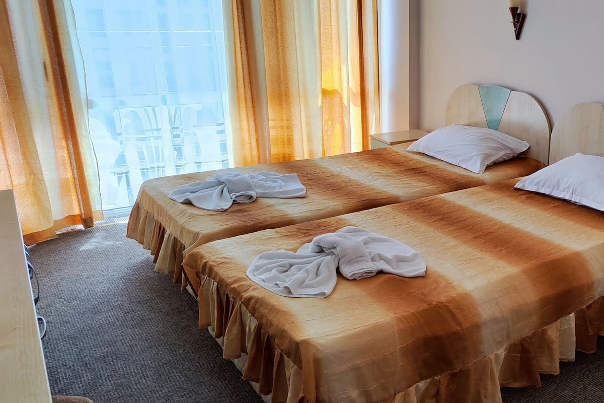 A hotel room with two beds, a chair, and a nightstand.