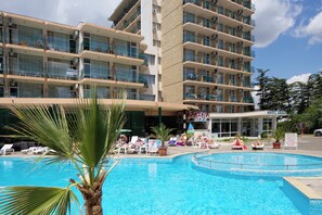 Um hotel com piscina, várias varandas e uma placa indicando um restaurante.