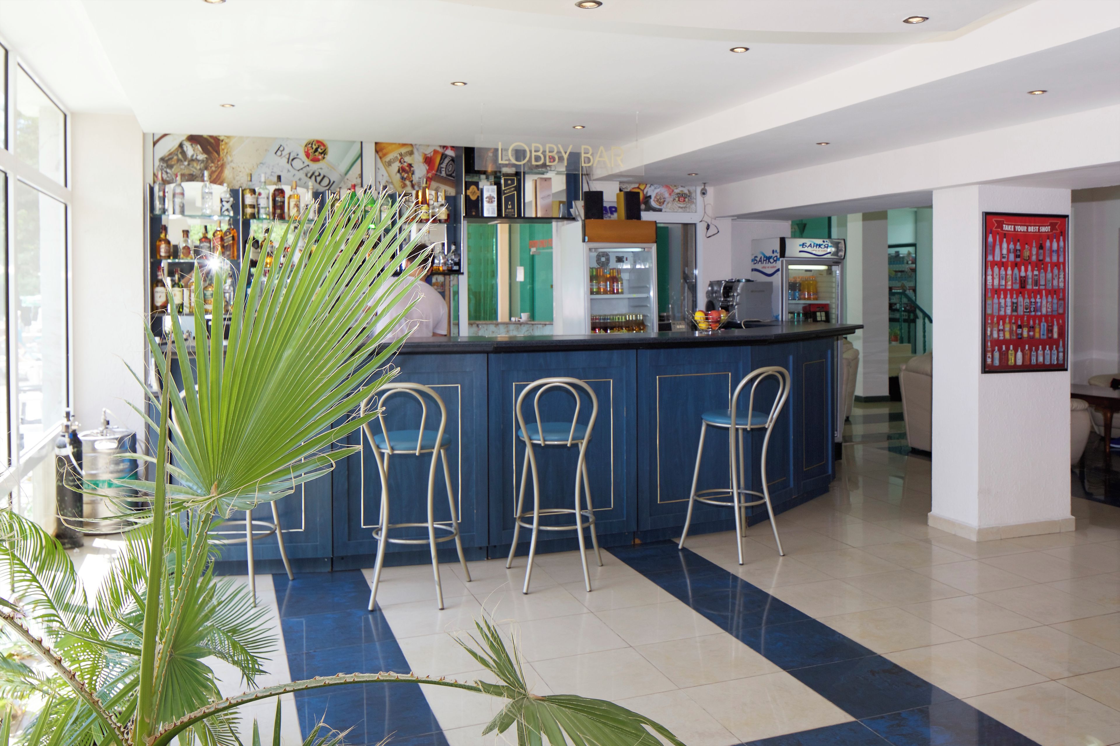 Zona de bar amb una barra, tres tamborets i un refrigerador.