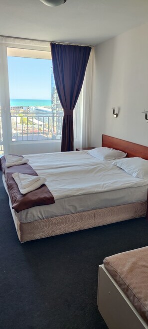 Une chambre d’hôtel avec un grand lit, une vue sur la mer et un balcon.