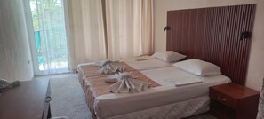 Habitación de hotel con dos camas, cabecero de madera, mesita de noche y vistas a zonas verdes.