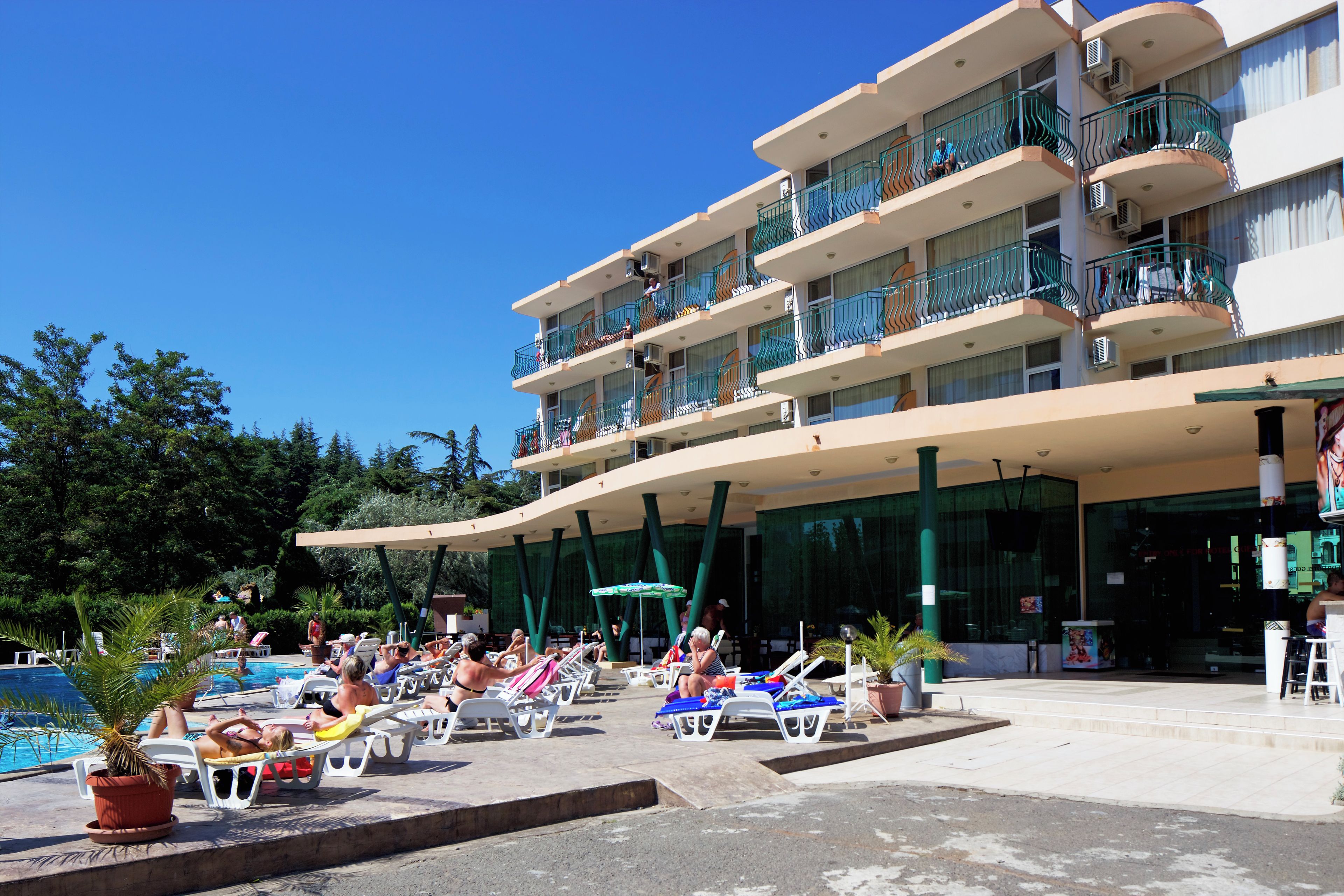 A hotel with a pool area, multiple balconies, and a covered seating area.