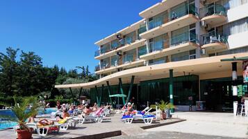 A hotel with a pool area, multiple balconies, and a covered seating area.