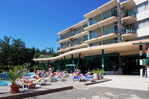 Un hotel con zona de piscina, varios balcones y un área de estar techada.