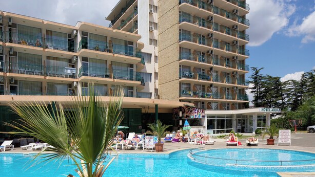 A hotel with a swimming pool, multiple balconies, and a sign indicating a restaurant.