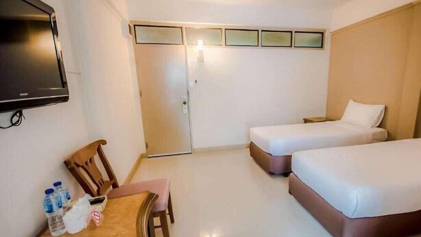 Une chambre d’hôtel équipée d’une télévision, d’un bureau avec une chaise, de deux lits et d’une porte.