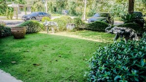 Un jardin bien entretenu, avec une pelouse, plusieurs grands pots décoratifs et une variété de plantes.