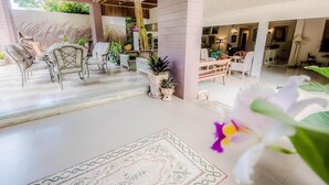 Un vaste espace de vie agrémenté d’un grand tapis, de plusieurs coins salon et de plantes en pot.