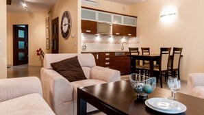 A modern living room with a sofa, a dining table with chairs, and a kitchen in the background. - Exclusive Apartments (Wroclaw)
