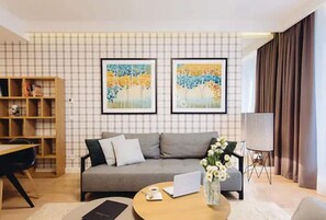 A modern living room with a grey sofa, a wooden bookshelf, a round coffee table, and two framed artworks on the wall. - Exclusive Apartments (Wroclaw)