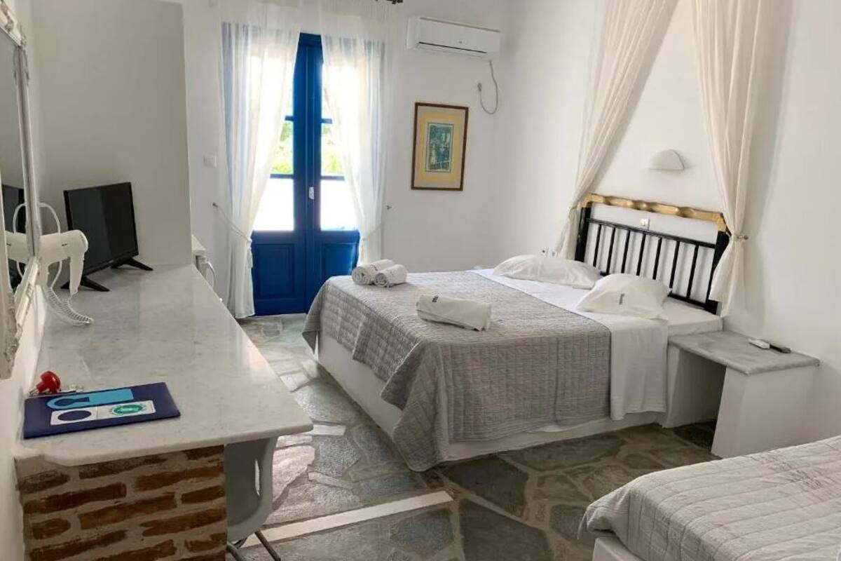 Un dormitorio con cama, mesita de noche y escritorio con silla.